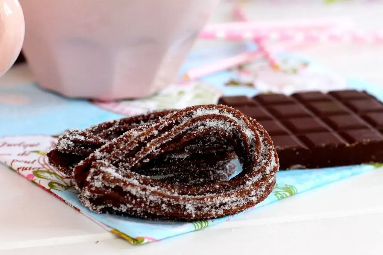 Churros azucarados y una barra de chocolate, perfectos para aprender como hacer churros caseros.