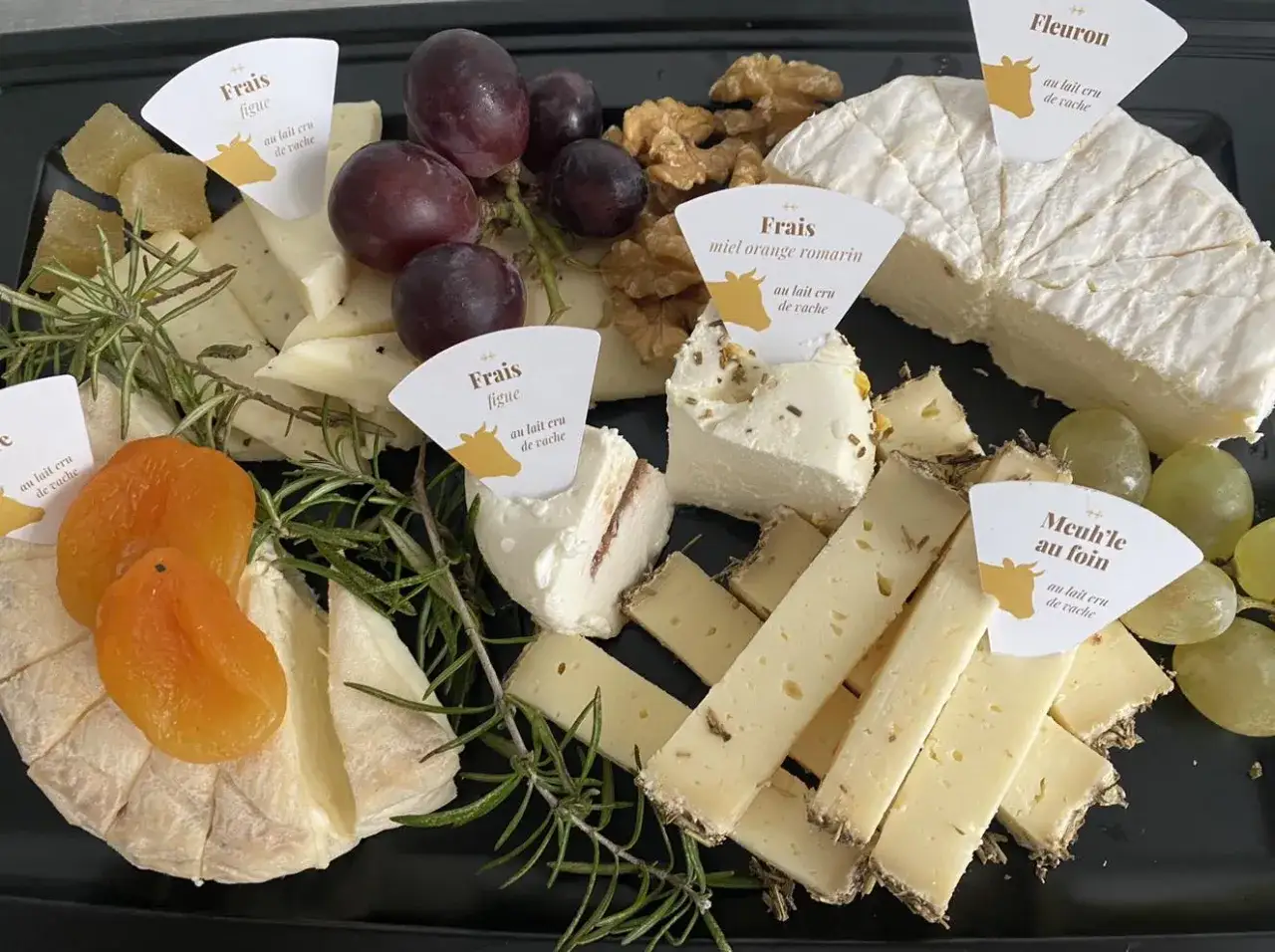 Plateau de fromages vari&eacute;s, dont un fromage frais au lait cru de vache, agr&eacute;ment&eacute; de fruits secs, raisins et herbes.