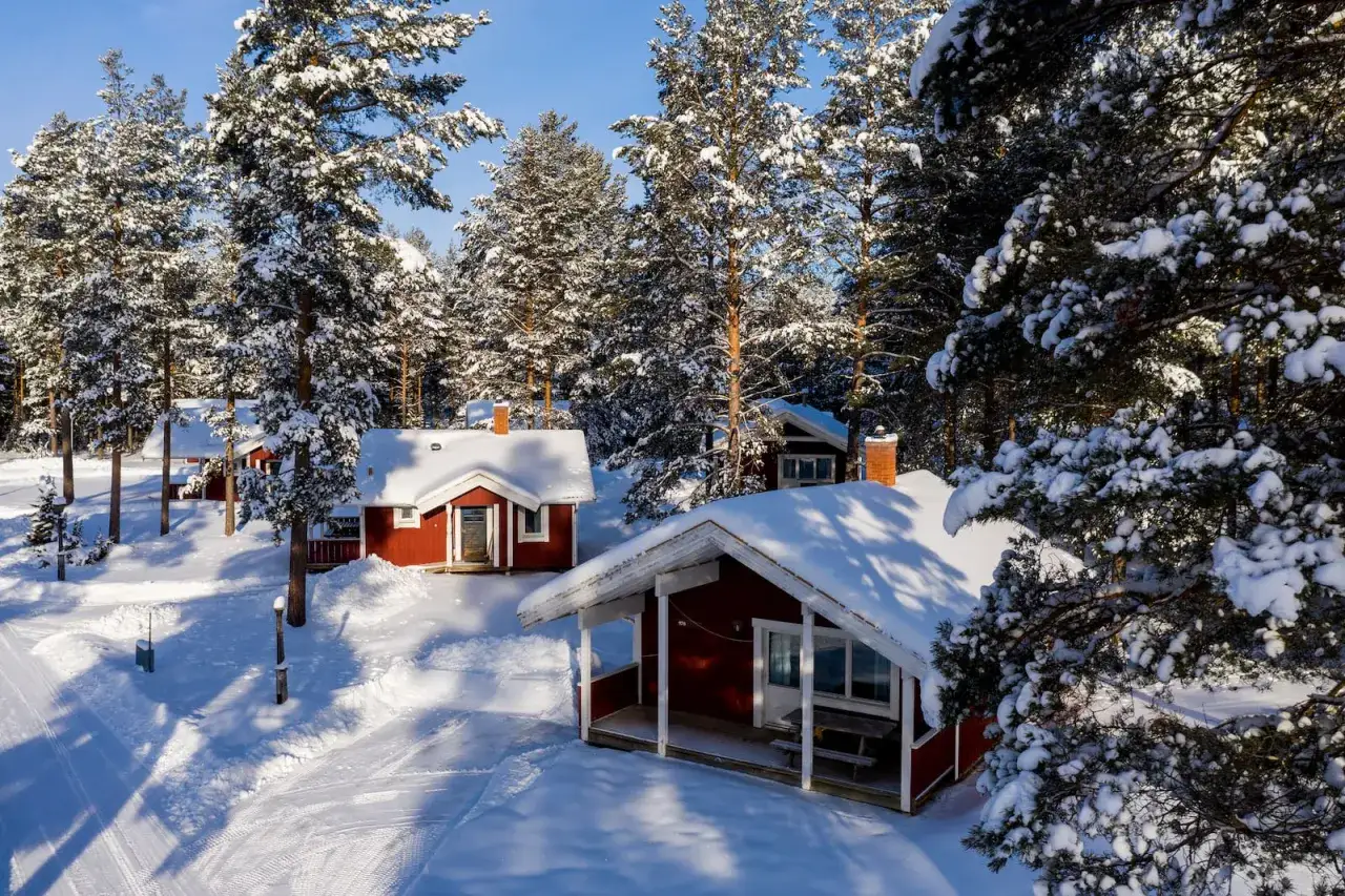 R&ouml;da stugor med sn&ouml;tyngda tak i en vinterlund vid Oskarshamn Gunnars&ouml;. En idyllisk vinterscen.