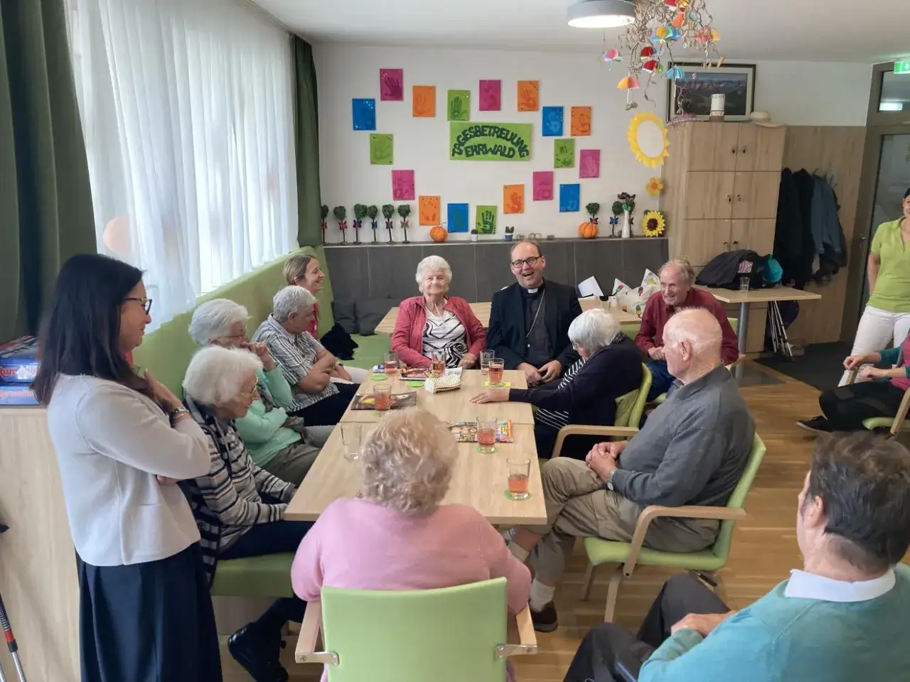 Eine Gruppe &auml;lterer Menschen und ein Geistlicher lachen und unterhalten sich bei einem Treffen. Sie scheinen zu wissen, was ist das wichtigste im Leben: Gemeinschaft und Freude.