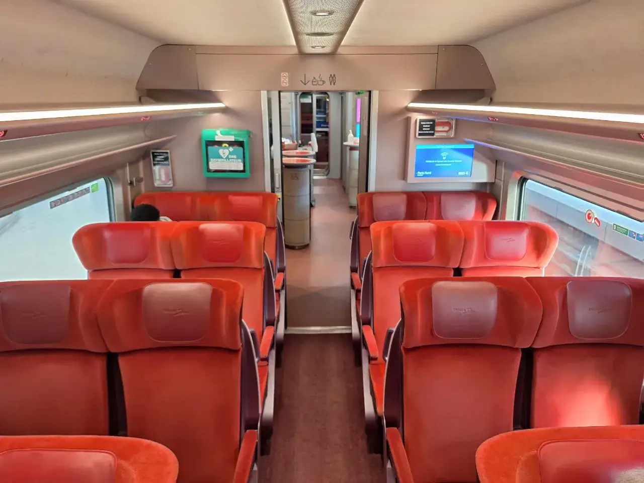 Interior of a train carriage with rows of red velvet seats, ready for the rotterdam to paris train journey.