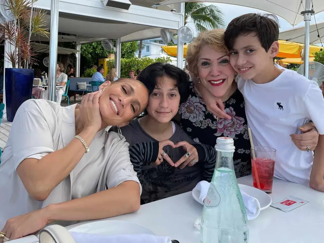 Jennifer Lopez z dziećmi i mamą cieszą się wspólnym posiłkiem. Uśmiechnięta rodzina przy stole.