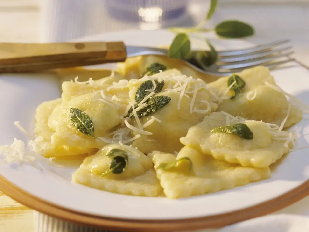 Ein Teller mit köstlichen Ravioli Pasta, garniert mit frischem Salbei und geriebenem Parmesan. Ein Genuss für Augen und Gaumen.