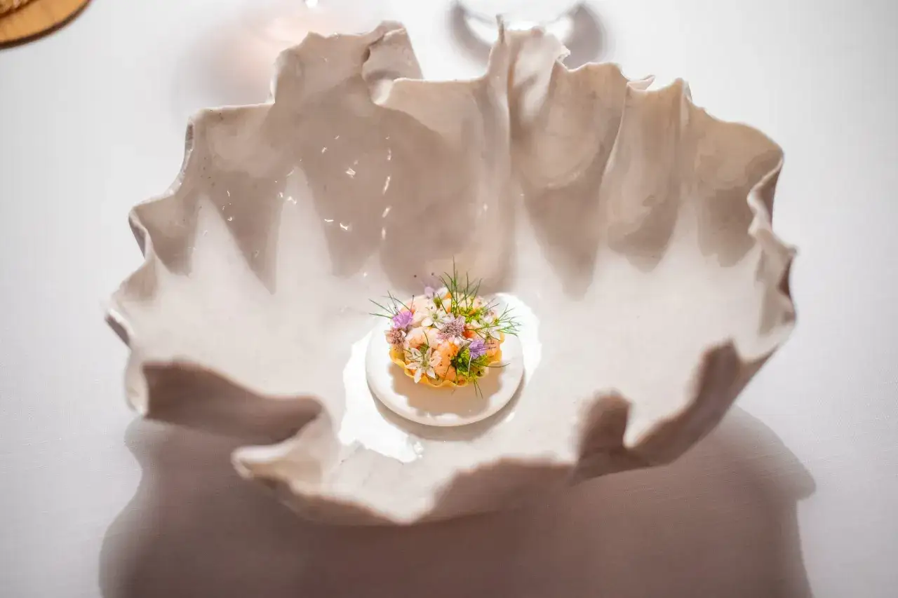 Delicioso aperitivo con gambas y flores comestibles, parte de un men&uacute; estrella Michelin.