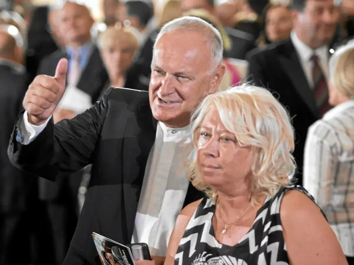 Jacek Cygan z synem, uśmiechnięty mężczyzna w garniturze pokazuje kciuk w górę. Obok niego stoi kobieta.