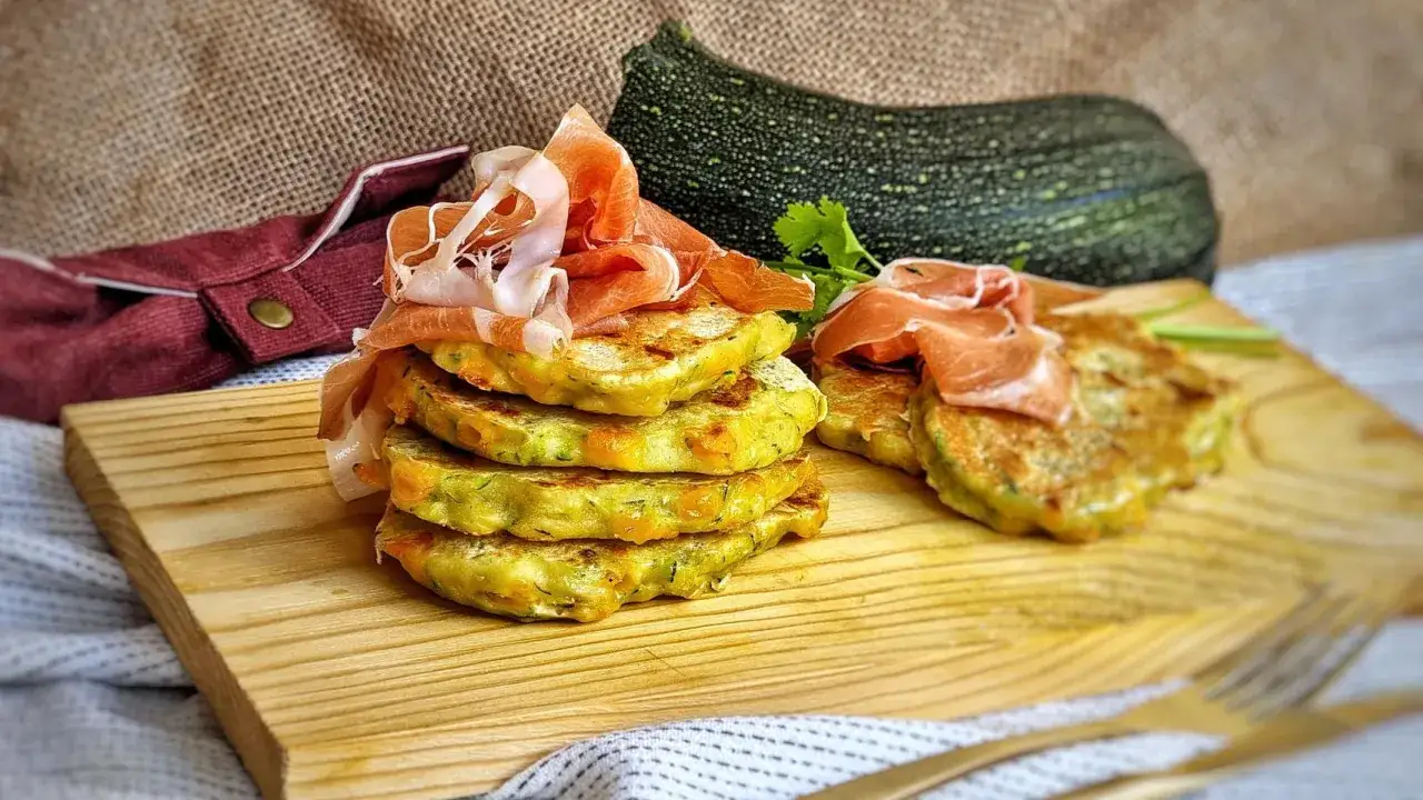 Deliciosas tortitas de calabacín apiladas, coronadas con jamón serrano. Un plato rústico y apetitoso.