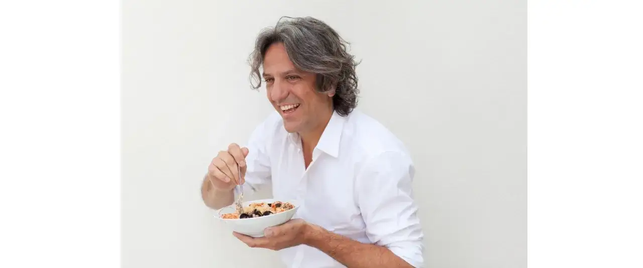 Giorgio Locatelli lacht und isst eine Schüssel mit Meeresfrüchten.