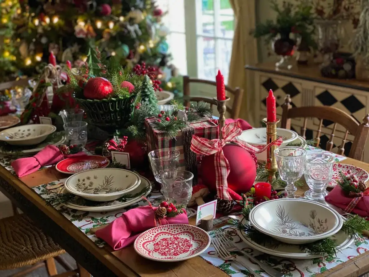 En vacker, modern juldukning med röda detaljer, granris och julgranspynt. En inbjudande dukning för en mysig jul.
