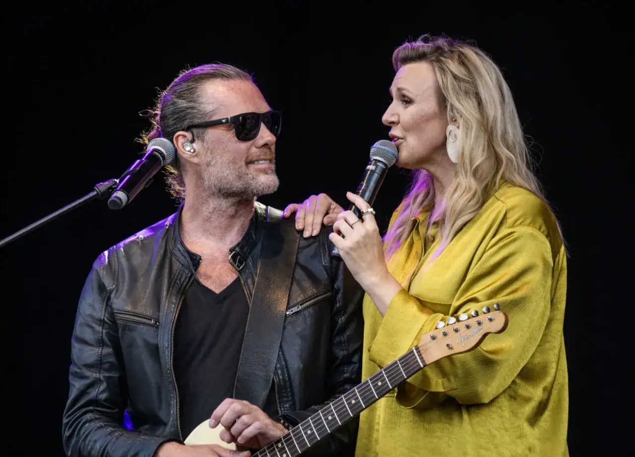Sanna Nielsen och en manlig musiker uppträder på scen. Mannen, med solglasögon och läderjacka, spelar gitarr.