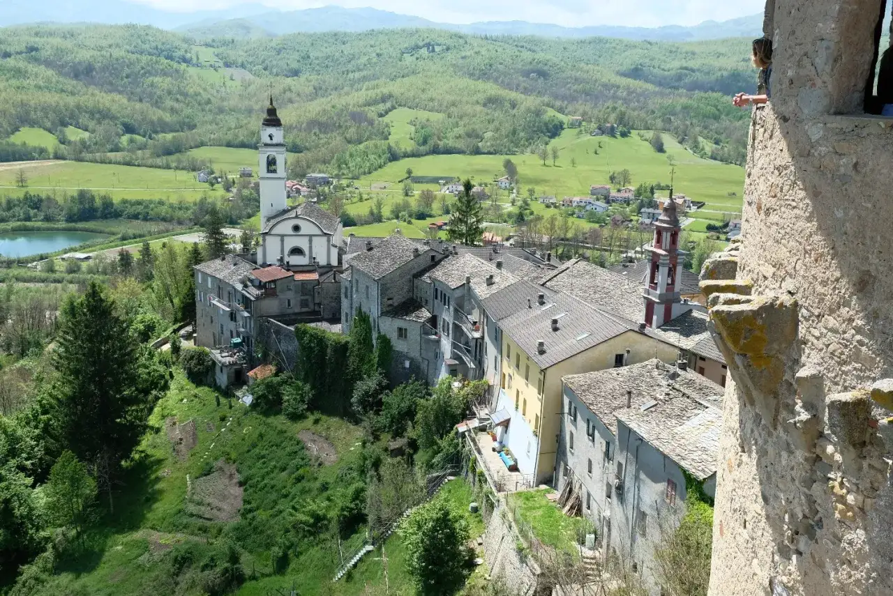 Borgo di Compiano, Parma, con case in pietra e torri campanarie, immerso nel verde delle colline.