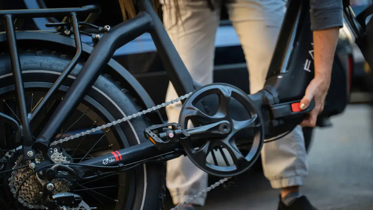Nahaufnahme eines E-Bikes mit Kette und Kurbel. Eine Hand hält den Akku, um den Bosch CX Gen 4 leiser machen zu können.