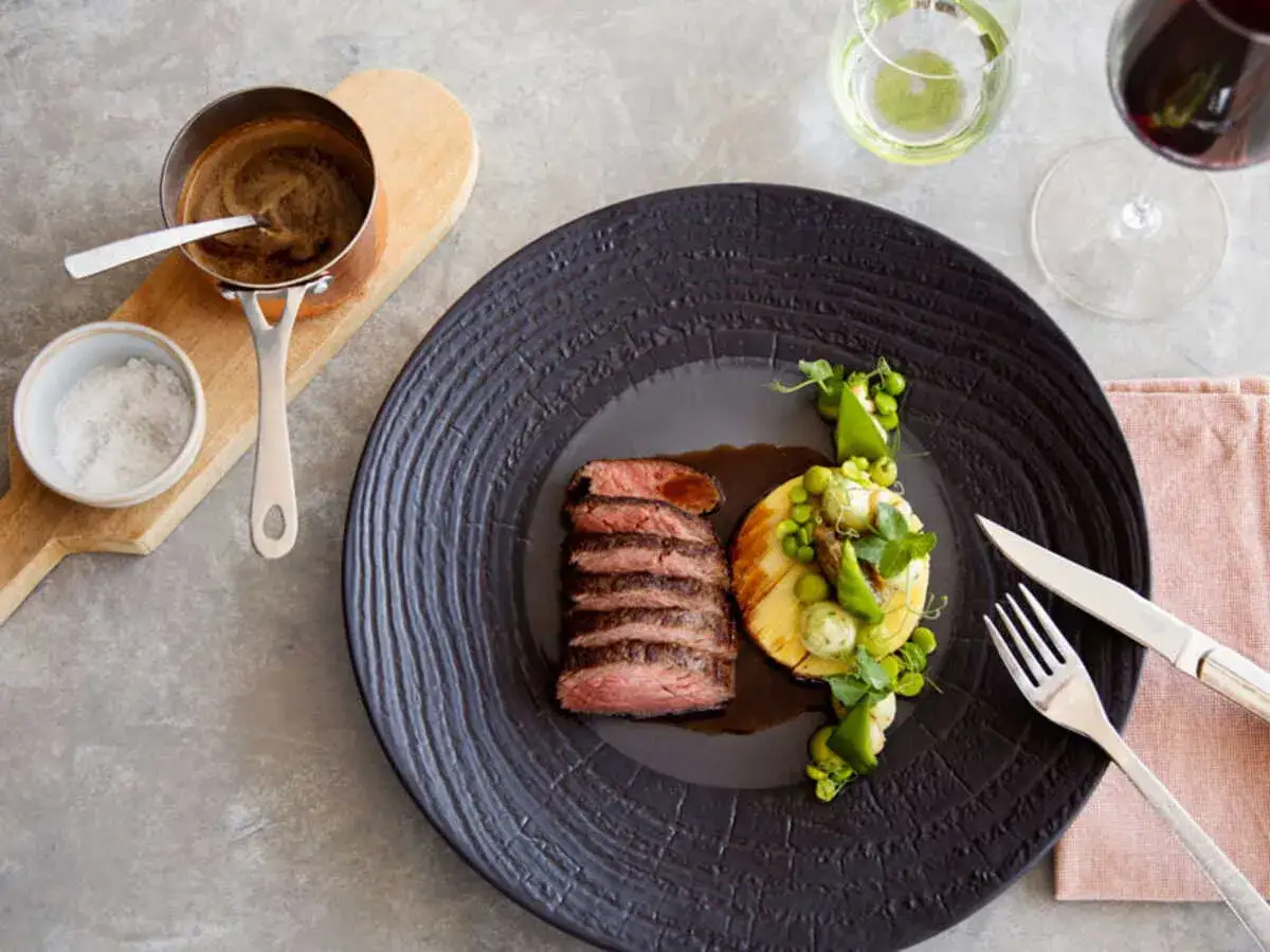 Filet mignon tranché, servi avec une purée de pommes de terre, des petits pois et une sauce au poivre. Une recette de filet mignon moelleux à déguster.