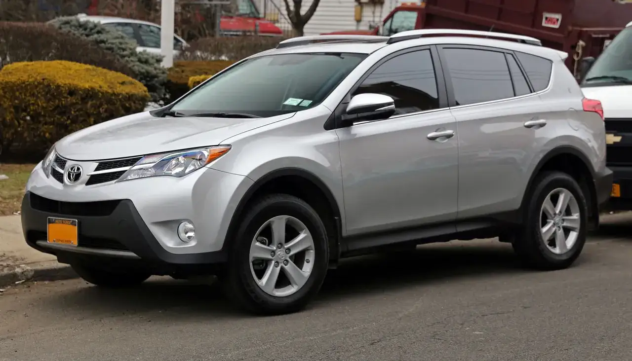 Srebrna Toyota RAV4 Hybrid zaparkowana na ulicy. Zastanawiasz się, ile pali Toyota RAV4 Hybrid? Ten model jest znany z oszczędności.