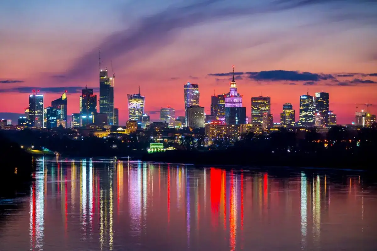 Warszawa nocą, rozświetlona wieżowcami, zachwyca odbiciami w Wiśle. Idealne miejsce na wieczorne atrakcje dla dorosłych.