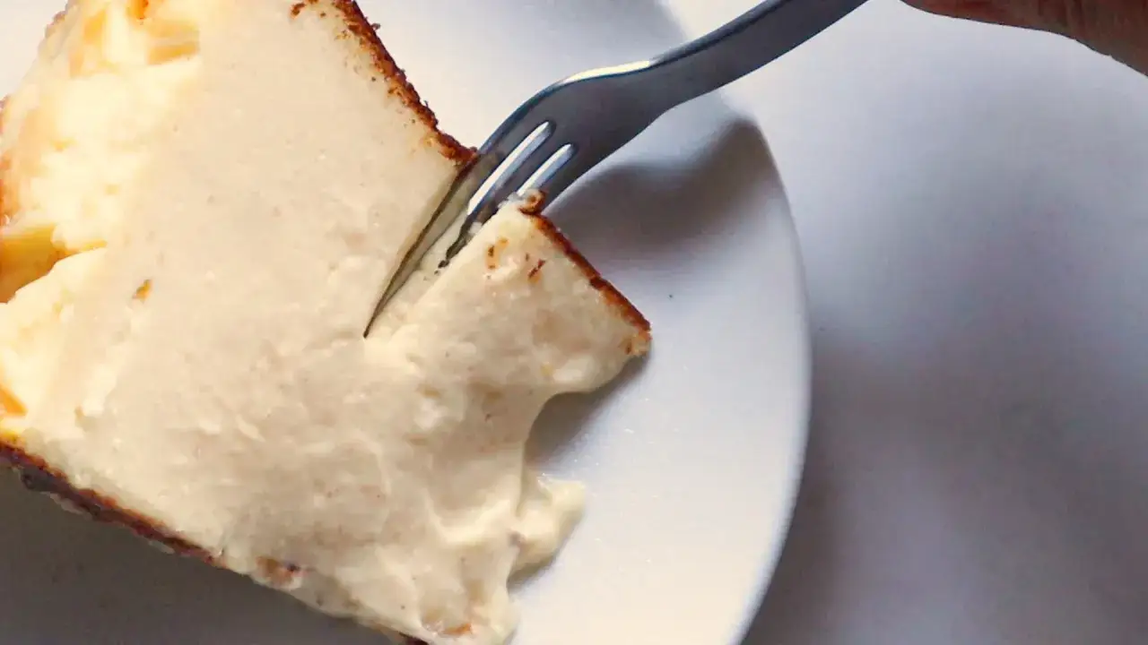 En bit krämig baskisk cheesecake med en gaffel som skär i den.