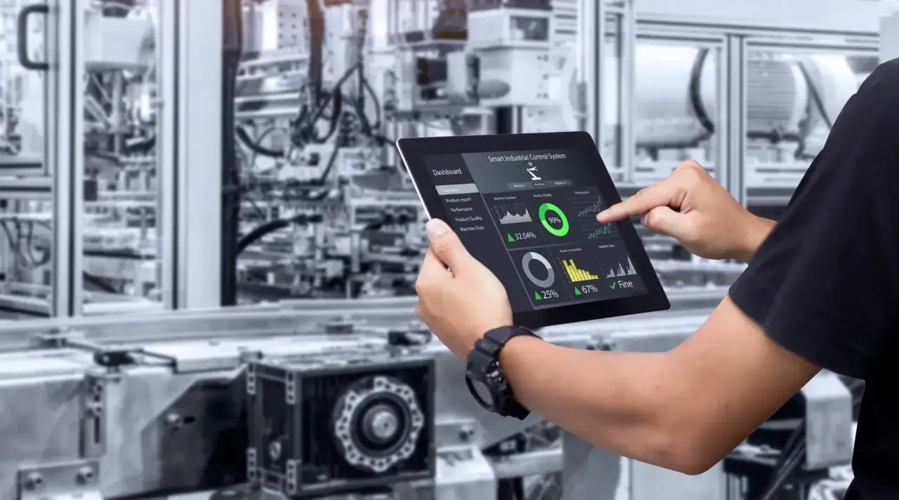 Un operatore usa un tablet per monitorare la produzione in una fabbrica moderna, mostrando la definizione di industria 4.0 con dati in tempo reale.