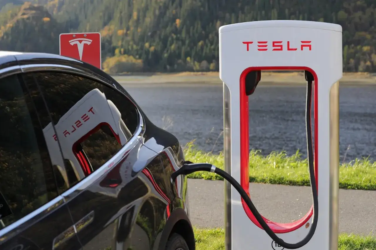 Czarna Tesla podłączona do ładowarki. Czy ładowanie Tesli jest darmowe? Zależy od lokalizacji i planu.
