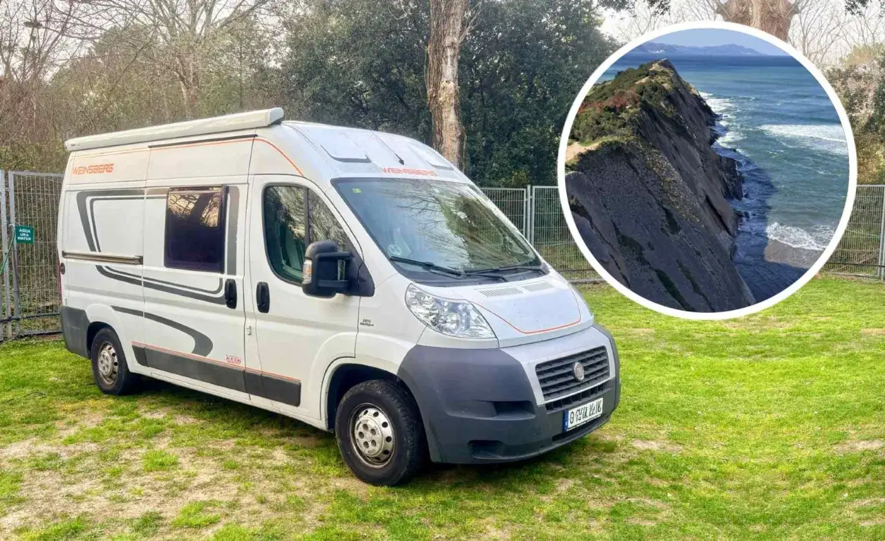Autocaravana blanca lista para viajar trabajando, con vista a un acantilado y el mar.