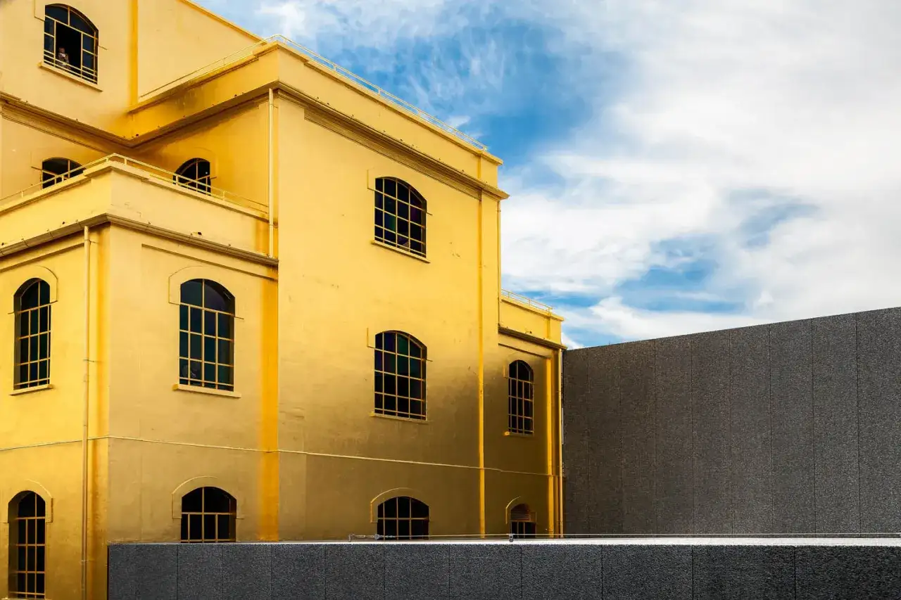 A striking golden building, a piece of art in Milan, stands against a blue sky with wispy clouds.