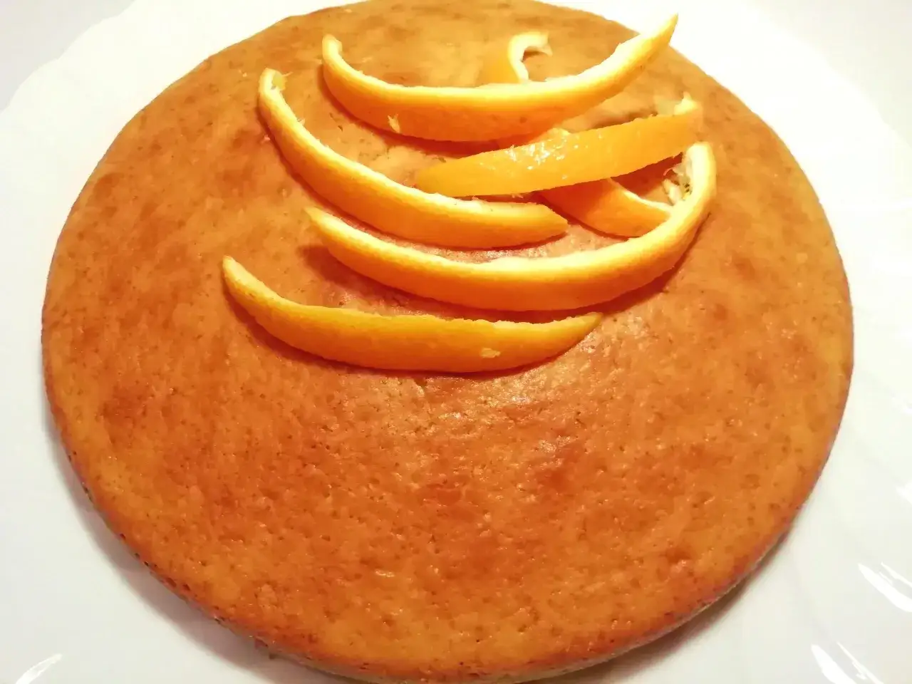 Torta all'arancia morbidissima, decorata con scorzette fresche. Un dolce profumato e invitante, perfetto per ogni occasione.