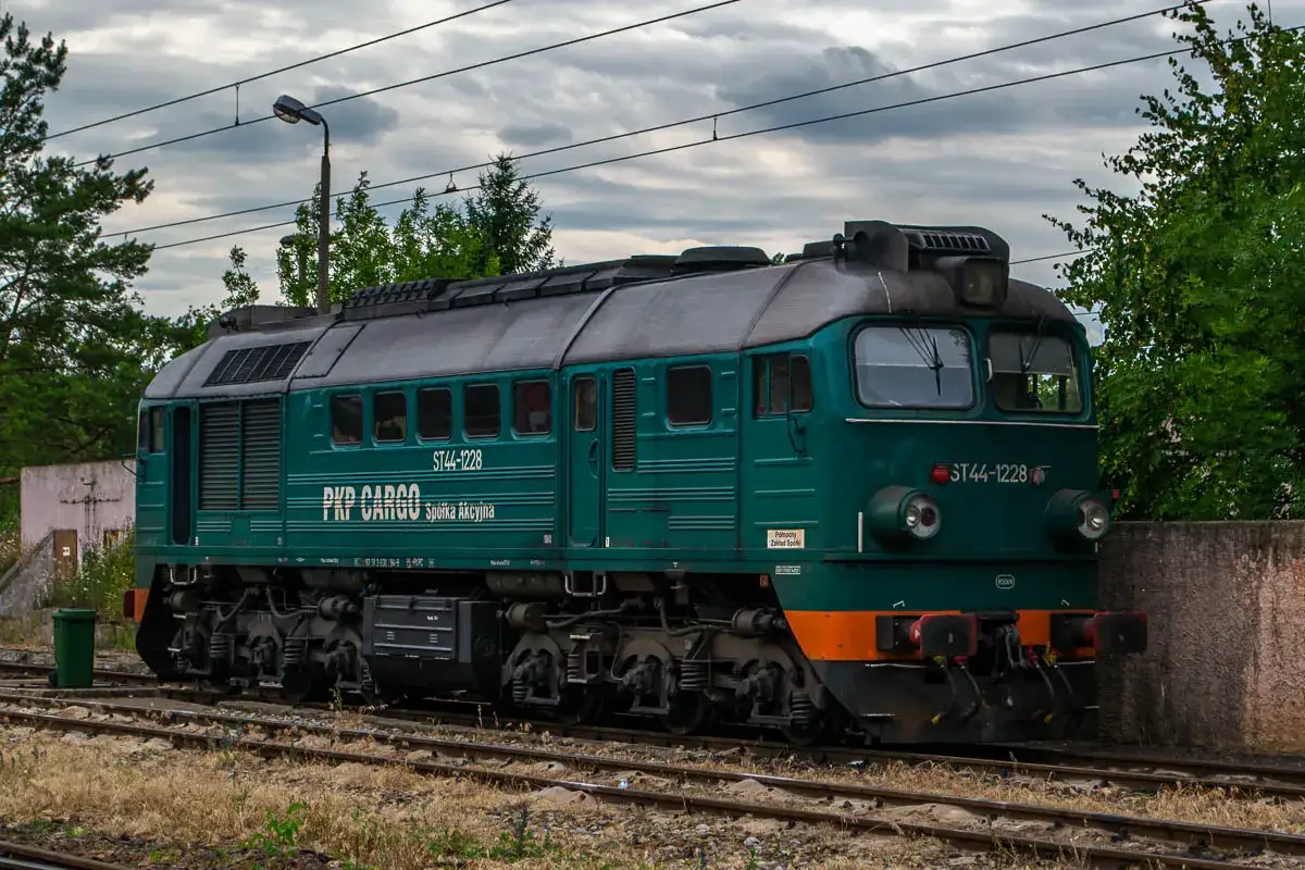 Zielona lokomotywa ST44-1228 PKP Cargo stoi na torach, gotowa do pracy.
