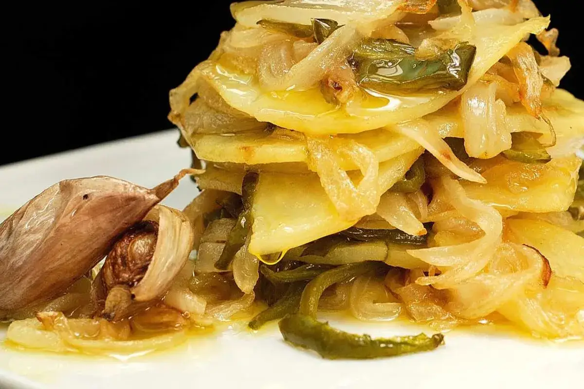 Deliciosas patatas salteadas con pimientos y cebolla, un cl&aacute;sico de las recetas con patatas, acompa&ntilde;adas de ajos asados.