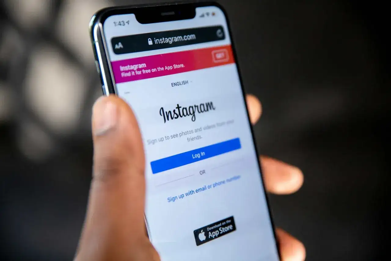 Dłoń trzyma smartfon z otwartą stroną logowania do Instagrama. Czas na stworzenie swojego profilu!
