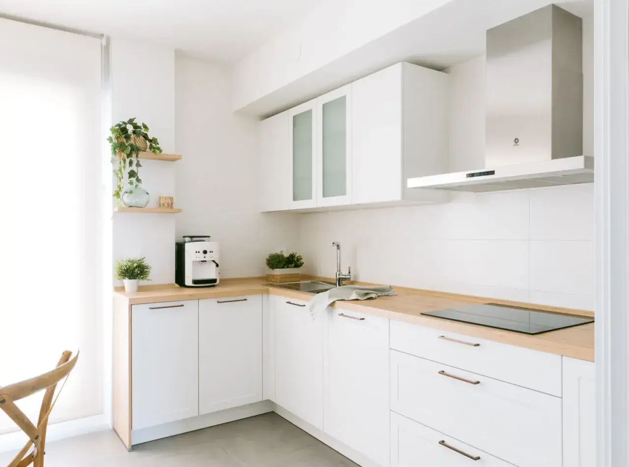 Diseños de cocinas pequeñas y sencillas: gabinetes blancos, encimeras de madera, cafetera y campana extractora moderna.