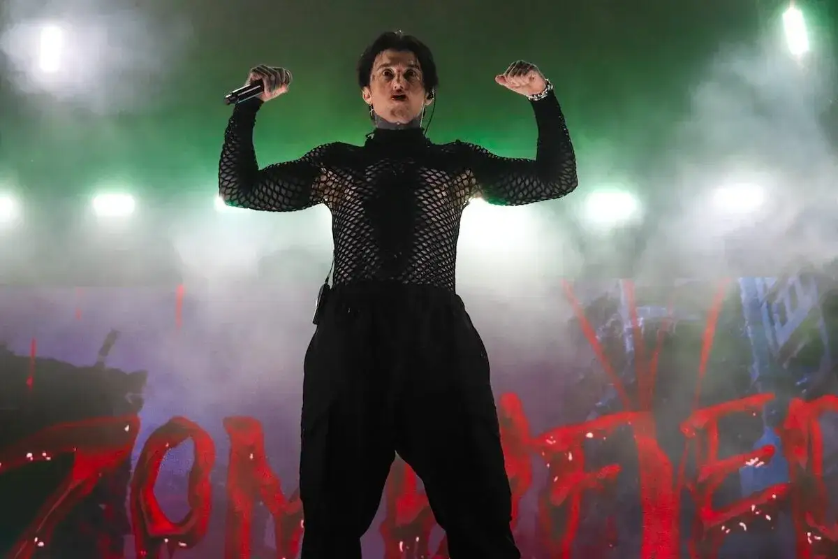 Ronnie Radke, membre de Falling In Reverse, pose sur sc&egrave;ne, bras lev&eacute;s, micro en main, sous des lumi&egrave;res vertes et un brouillard.