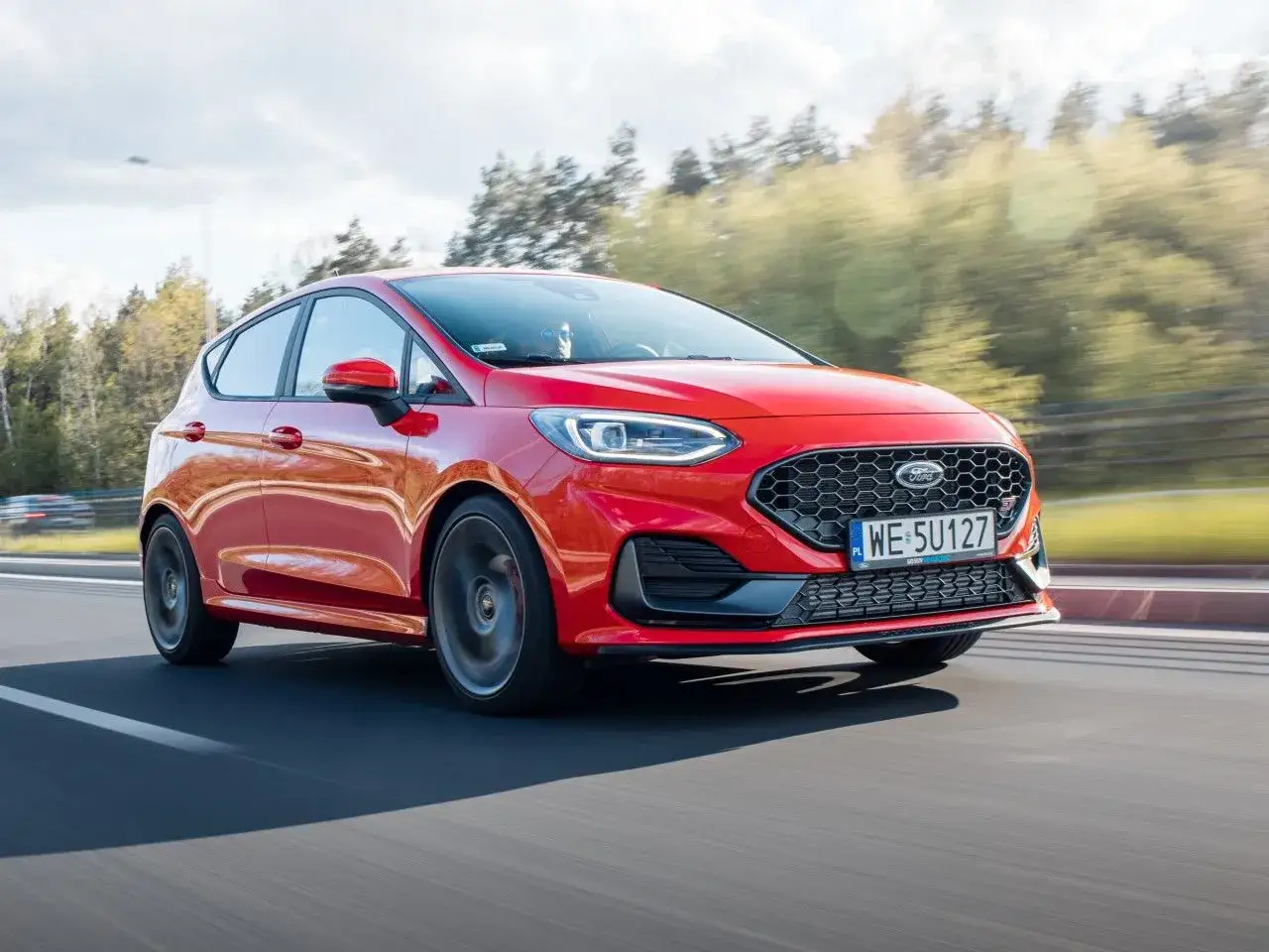 Czerwony Ford Fiesta MK7 w ruchu, z widocznymi felgami i oponami. Idealny rozmiar opon dla tej sportowej wersji.