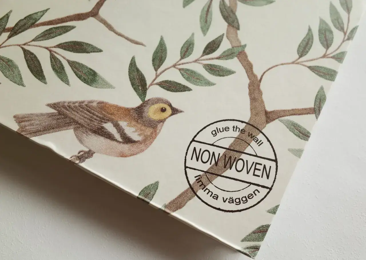 Detalj av tapetsera non woven med f&aring;gel och grenar. Texten 