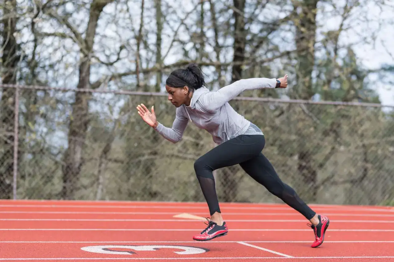 Athlète en pleine action sur la piste, concentrée pour sa séance VMA. Elle s'élance avec puissance, prête à battre ses records.
