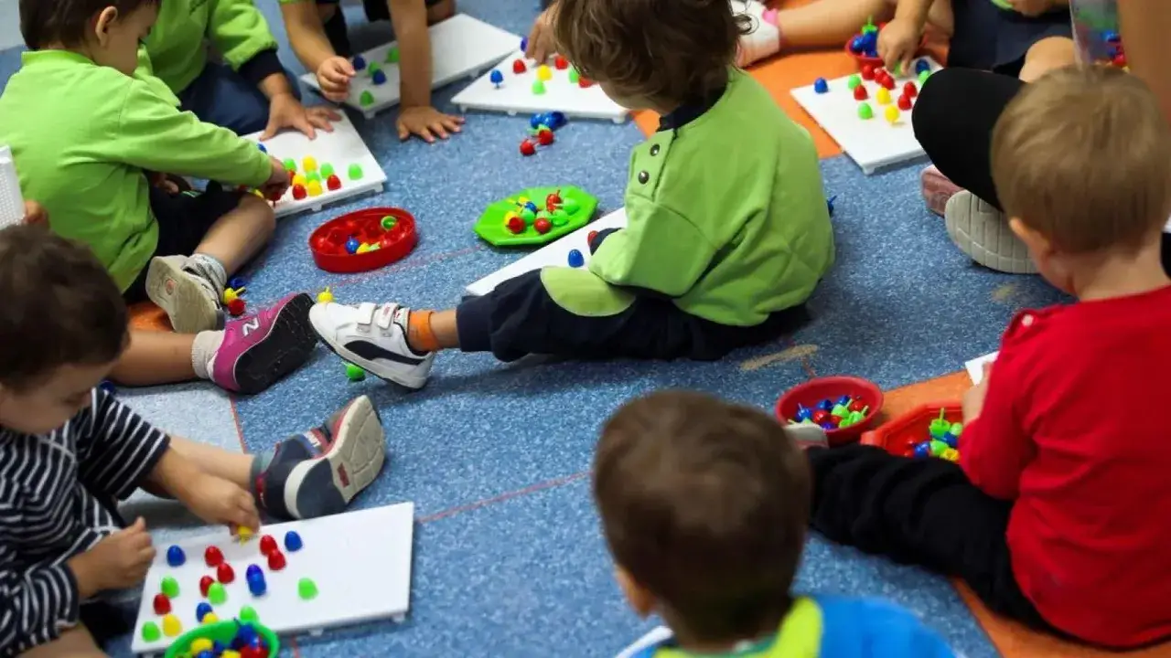 Ni&ntilde;os jugando con piezas de colores en una escuela infantil o guarder&iacute;a.