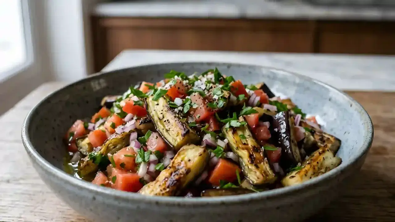 Salade colorée de notre recette aubergines grillées au four, avec tomates, oignons rouges et persil frais.