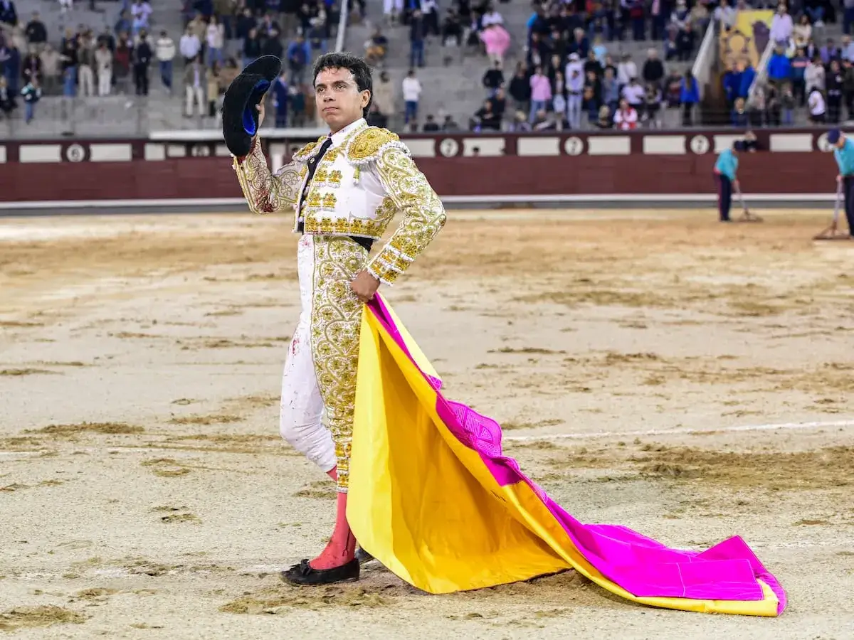 Juan de Castilla, torero, posa con su capote de paseo, amarillo y fucsia, en la arena.