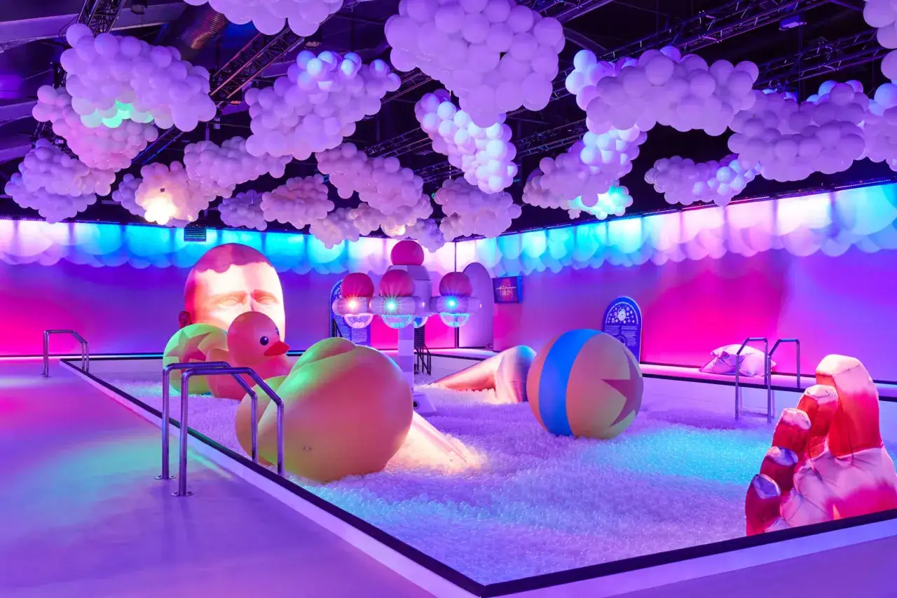 Un monde onirique à Paris : une piscine à balles géante sous des nuages de ballons, avec des jouets iconiques et une tête monumentale.