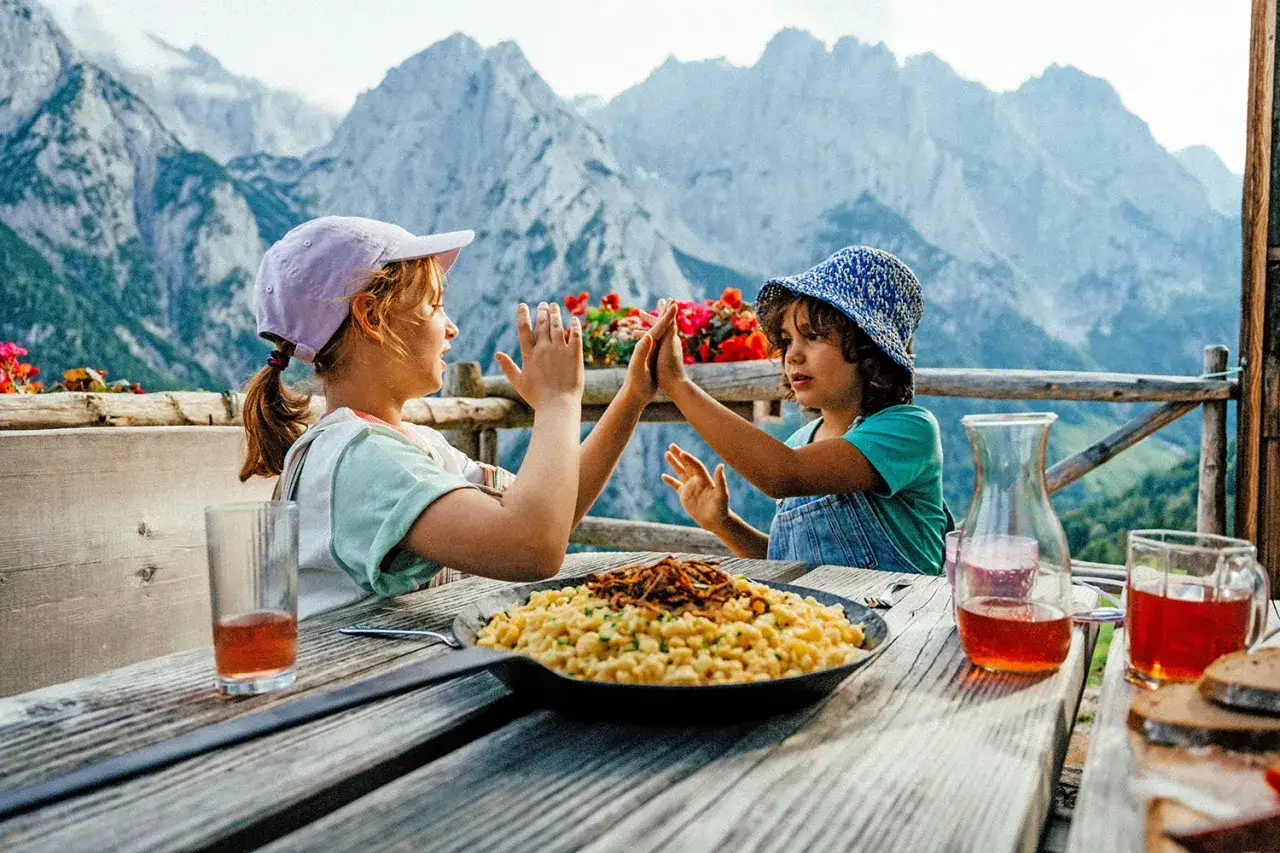 Due bambini si danno il cinque in montagna, godendosi un pasto delizioso con una vista mozzafiato.
