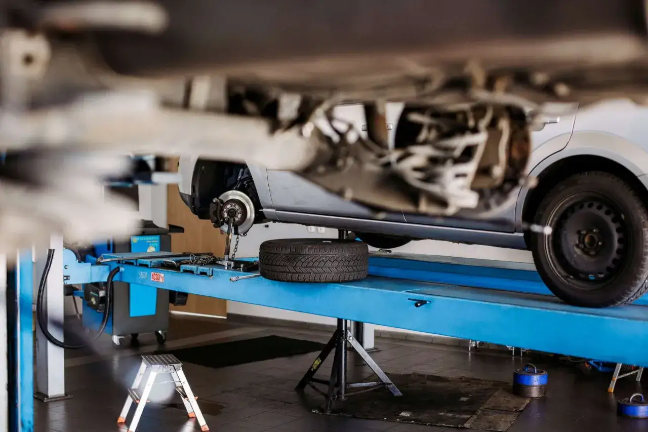 Auto sciaga na prawa strone, bo mechanik wymienia koło na podnośniku.