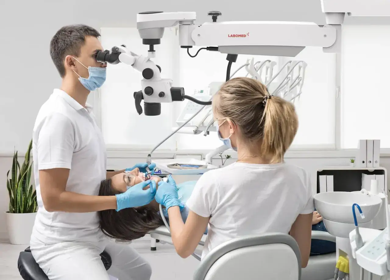 Dentysta pod mikroskopem wykonuje leczenie kanałowe. Ile wizyt potrzeba? Zależy od przypadku, ale precyzja jest kluczowa.