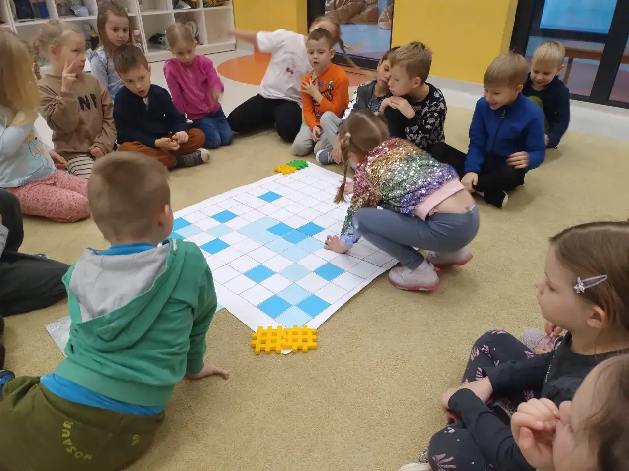 dzieci w przedszkolu realizujące projekt edukacyjny na dywanie