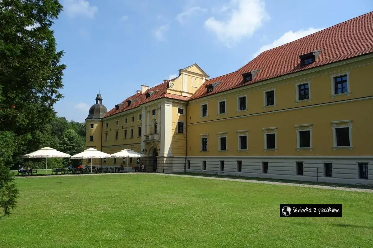 Ż&oacute;łty pałac z czerwonym dachem, gdzie można usiąść pod parasolami i poczuć klimat rudy raciborskie.