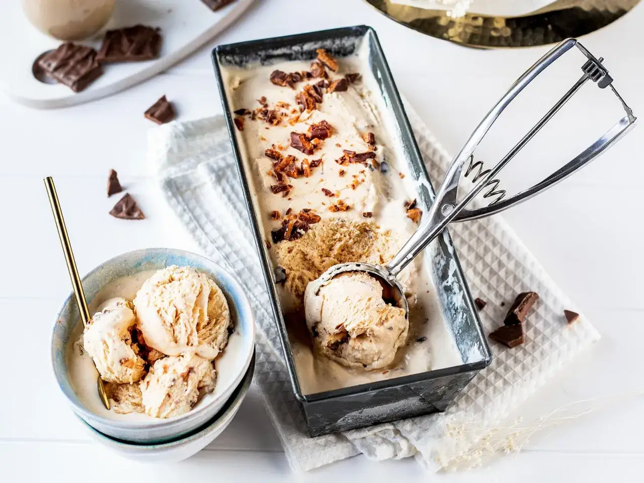 Cremiges Baileys Eis Rezept, garniert mit Schokostückchen. Ein Löffel Eis wird gerade aus der Form gehoben.