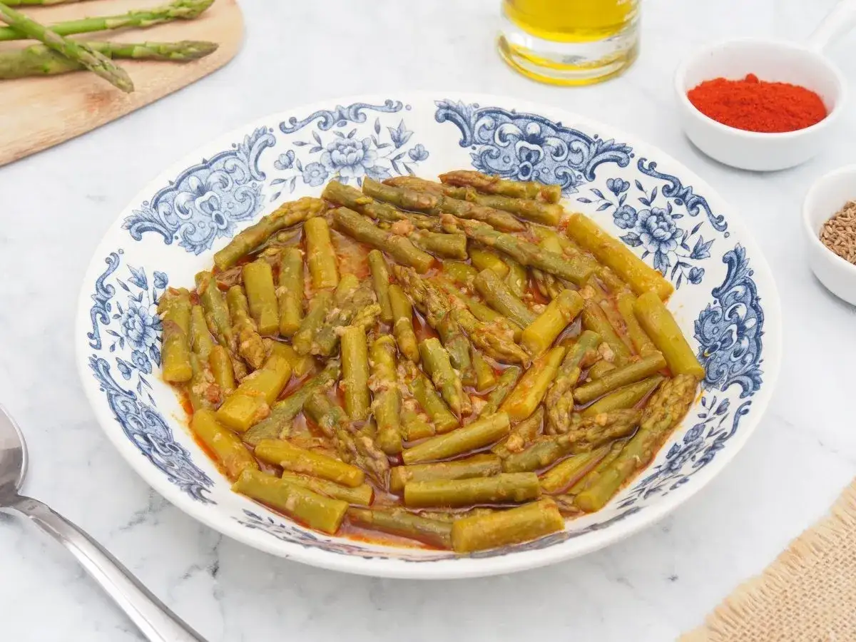 Plato de esparragos esparragados con ajo y pimentón, acompañado de aceite de oliva y especias.