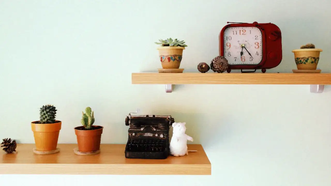 Ideas para decorar baldas sal&oacute;n: cactus, pi&ntilde;as, reloj retro, m&aacute;quina de escribir y un rat&oacute;n de peluche.