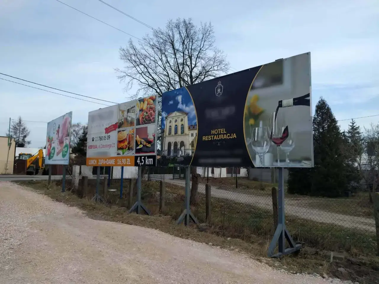 Rząd billboardów reklamuje hotel, restaurację, bistro i ofertę lunchową. Widać też budynek i kieliszki z winem.