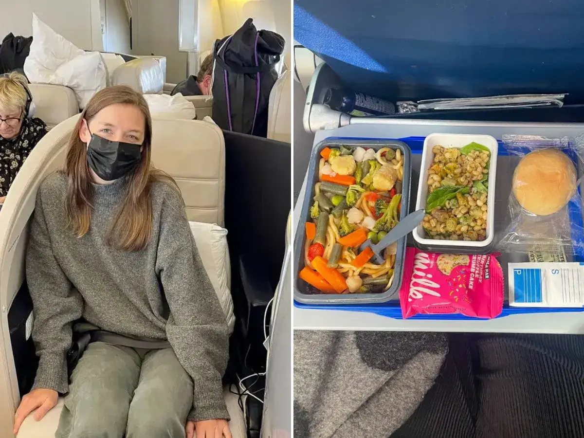 Kobieta w masce siedzi w samolocie, obok taca z posiłkami flydubai: makaron z warzywami, sałatka, bułka i batonik.
