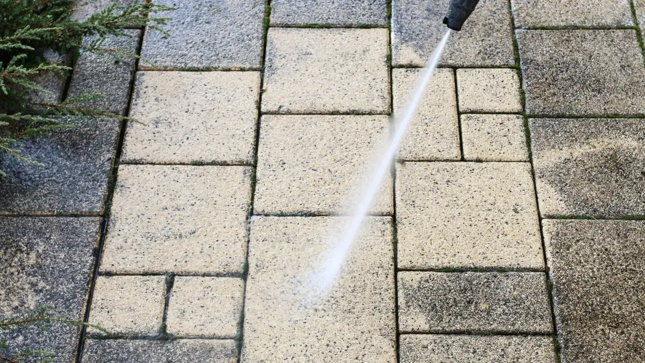 Mycie kostki brukowej myjką ciśnieniową. Widać różnicę między umytą a brudną powierzchnią. To prosty sposób, jak odnowić kostkę brukową.