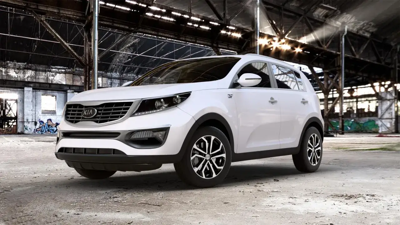 Biały Kia Sportage 2014 w opuszczonej hali przemysłowej, z graffiti na ścianach i światłem wpadającym przez dach.
