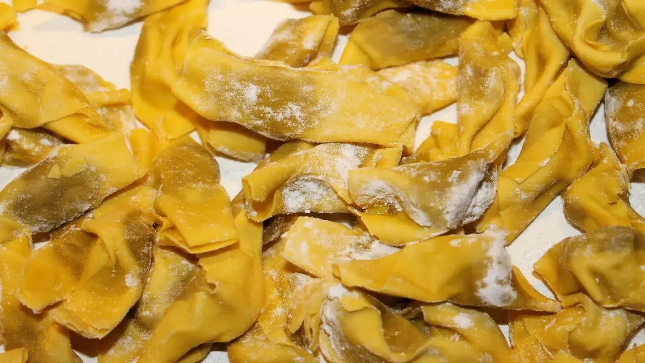 Un mucchio di ravioli bresciani freschi, spolverati di farina, pronti per essere cucinati.