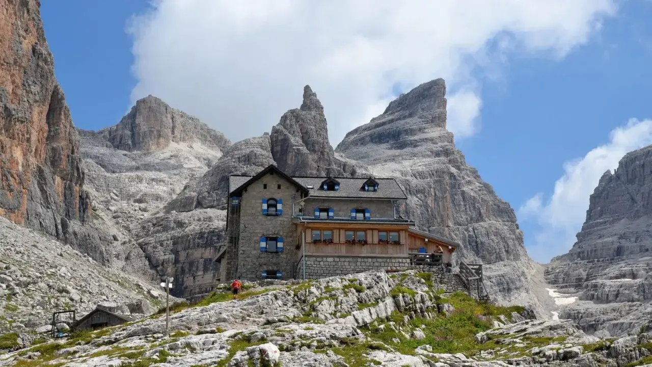 Il rifugio Tuckett e Sella, incastonato tra imponenti vette rocciose, offre un riparo accogliente agli escursionisti.